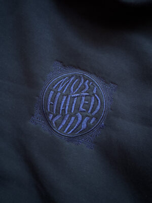 Close-up of the tonal embroidered Most Hated Kids logo on the MHK Navy Blue Hoodie.
