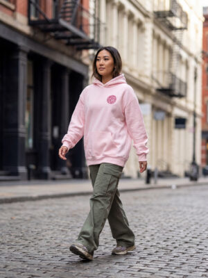 Female model wearing the Signature Pink Hoodie with the embroidered Most Hated Kids Signature logo.
